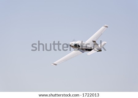 private aircraft - small propeller aircraft climbing and turning left against blue sky with copyspace, propeller motion blur