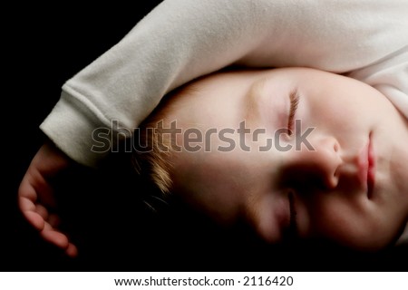 sleeping young boy in white sweater with arm rested over his head