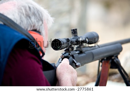 man laying down with rifle, taking aim. shot wide open, focus on front of scope