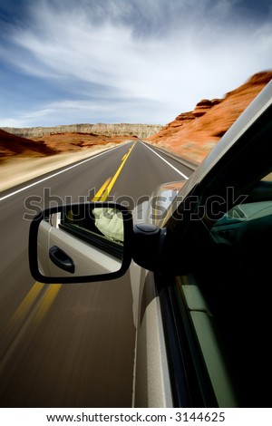 car driving through the Bighorn Canyon, Wyoming, with motion blur. SUV, focus on mirror.