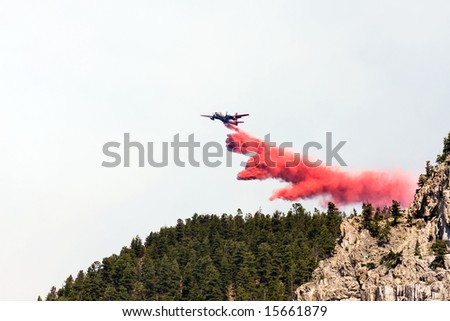 firefighting aircraft dumping red fire retardant chemical over forest during Montana fire fighting effort to help contain the spreading fire