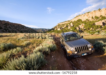 SUV in late sun driving on the foot of a mountain trail in Southern Montana. Blank Wyoming license plate.