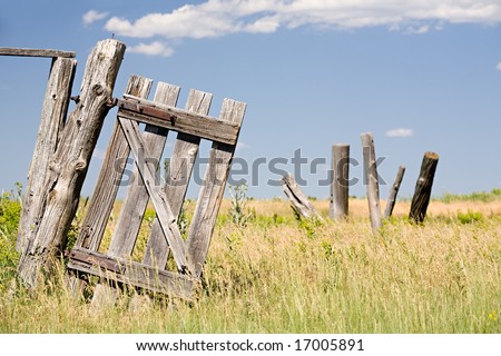 old broken fence door hangs crooked on a post