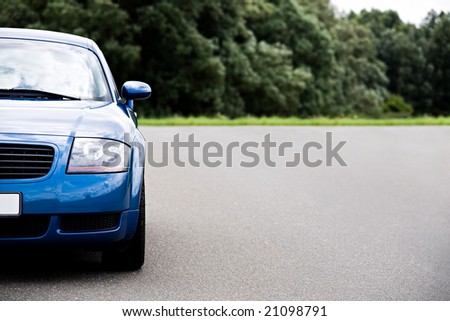 sports car - modern blue coupe on road, focus on headlight with ample copyspace