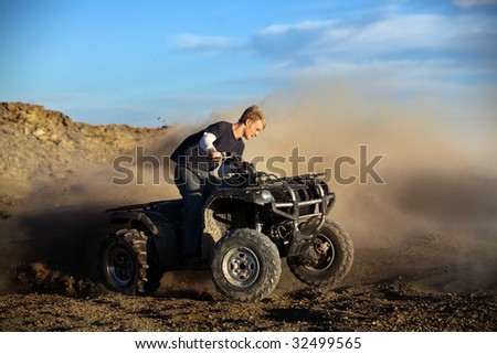 Teen male riding quad / four-wheeler 4x4 on the dirt
