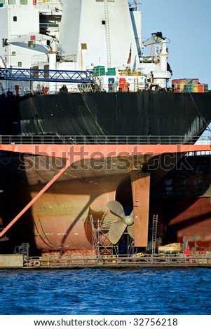freighter in dry dock with work being done on propeller