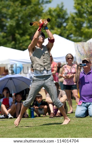 SUWANEE, GA - MAY 19:  A male circus performer slings and twirls balls of fire while performing at Arts In The Park, a spring festival held on May 19, 2012 in Suwanee, GA.