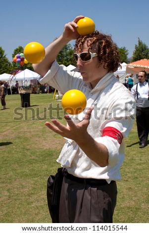 SUWANEE, GA - MAY 19:  A juggler tosses yellow balls in the air, as he performs at the Arts In The Park festival on May 19, 2012 in Suwanee, GA.  The juggler was part of the Imperial OPA Circus.