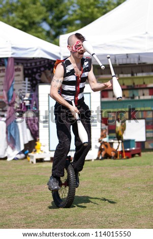 SUWANEE, GA - MAY 19:  A male circus performer juggles pins riding a unicycle while performing at the Arts In The Park festival on May 19, 2012 in Suwanee, GA. He performs for Imperial OPA Circus.