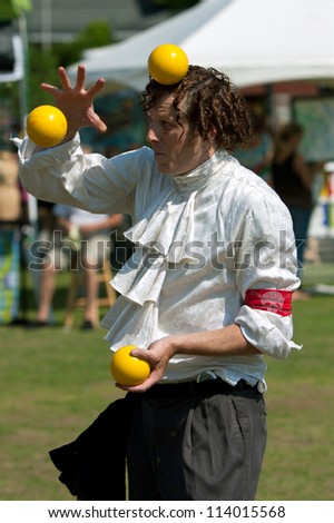 SUWANEE, GA - MAY 19:  A juggler tosses yellow balls in the air, as he performs at the Arts In The Park festival on May 19, 2012 in Suwanee, GA.  The juggler is part of the Imperial OPA Circus.