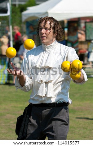 SUWANEE, GA - MAY 19:  A juggler tosses bright yellow balls in the air, as he performs at the Arts In The Park spring festival on May 19, 2012 in Suwanee, GA. The juggler was part of a local circus.