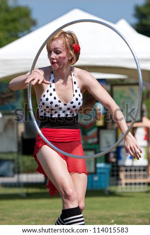 SUWANEE, GA - MAY 19:  A circus performer does the hula hoop, performing at the Arts In The Park spring festival on May 19, 2012 in Suwanee, GA. The performer is part of The Imperial OPA Circus.