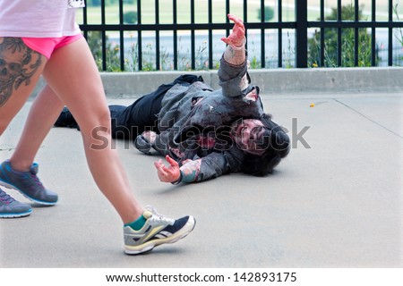 ATLANTA GA JUNE 8 A zombie lying on the asphalt reaches for women passing by in the Zombie Run on June 8 2013 in Atlanta GA Hundreds of runners dodged zombies in the 5K race ATLANTA GA JUNE 8 A zombie lying on the asphalt reaches for women passing by in the Zombie Run on June 8 2013 in Atlanta GA Hundreds of runners dodged zombies in the 5K race