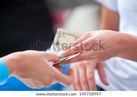 ATLANTA, GA - JULY 27:  Closeup of two women's hands exchanging money at a vendor booth at the 3rd Annual Atlanta Ice Cream Festival in Piedmont Park, on July 27, 2013 in Atlanta.