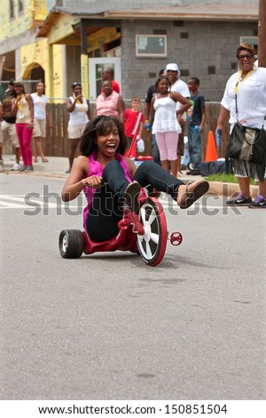 ATLANTA, GA - AUGUST 3:  An unidentified young woman rides downhill on a Big Wheel at the Cool Dads Rock Soap Box Derby, at the Old 4th Ward Park on August 3, 2013 in Atlanta.