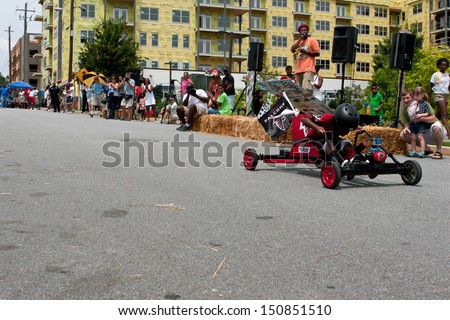 ATLANTA, GA - AUGUST 3:  An unidentified kid steers his car down a street as onlookers cheer in the Cool Dads Rock Soap Box Derby, at the Old 4th Ward Park on August 3, 2013 in Atlanta.