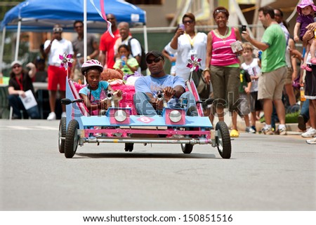 ATLANTA, GA - AUGUST 3:  A father and daughter steer their homemade car down a hilly street in the Cool Dads Rock Soap Box Derby, held at the Old 4th Ward Park on August 3, 2013 in Atlanta.
