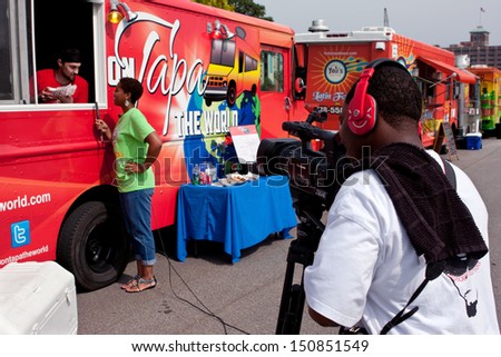 ATLANTA, GA - AUGUST 3:  A cameraman shoots a feature reporter interviewing a food truck employee at the Cool Dads Rock Soap Box Derby, at the Old 4th Ward Park on August 3, 2013 in Atlanta.