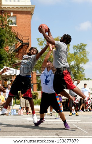 ATHENS, GA - AUGUST 24: Three young men fight for a rebound while playing in a 3-on-3 basketball tournament held on the streets of downtown Athens, on August 24, 2013 in Athens, GA.