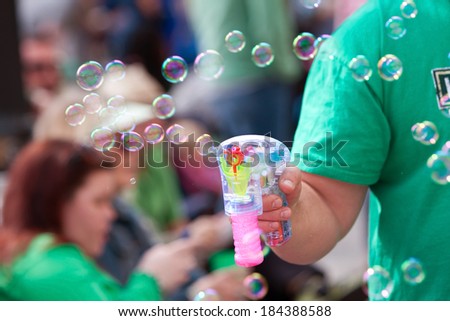 ATLANTA, GA - MARCH 15:  A man uses a bubble gun to blow bubbles at the St. Patrick\'s Day parade on Peachtree Street, on March 15, 2014 in Atlanta, GA.
