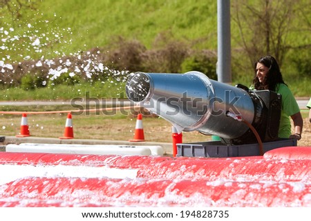 ATLANTA, GA - APRIL 5:  A young woman operates a large bubble machine to fill the foam pit with soap suds, at the Ridiculous Obstacle Challenge (ROC) 5K race, on April 5, 2014 in Atlanta, GA.