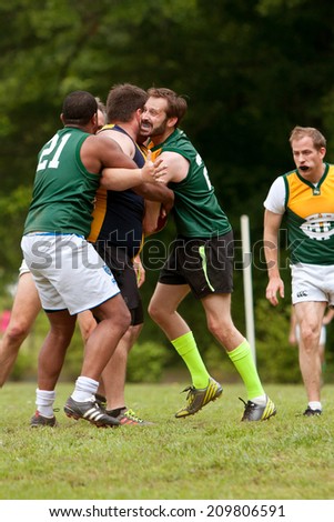 ROSWELL, GA - MAY 17:  A player gets tackled in an amateur game of Australian Rules Football in a Roswell city park, on May 17, 2014 in Roswell, GA.
