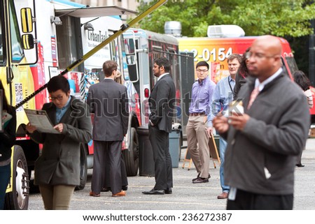 ATLANTA, GA - OCTOBER 16: Customers stand in line to order meals from food trucks during their lunch hour, at \