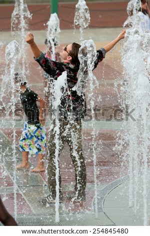 ATLANTA, GA - SEPTEMBER 6:  A young man stands triumphantly while getting soaked wearing street clothes in the fountain at Centennial Park on September 6, 2014 in Atlanta, GA.