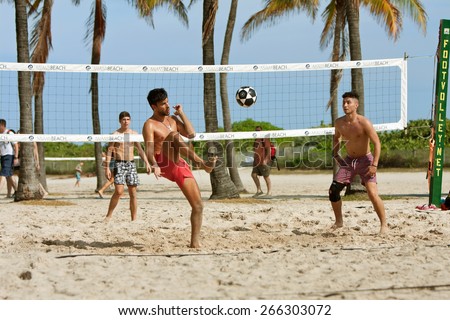 MIAMI, FL - DECEMBER 27:   Young men kick a soccer ball over the net while playing foot volley on the beach volleyball courts at a public beach off Ocean Drive, on December 27, 2014 in Miami, FL.