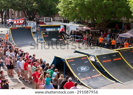 ATHENS, GA - APRIL 25:  A large crowd watches a young BMX pro perform spectacular tricks in the pro BMX competition at the annual Athens Twilight Criterium, on April 25, 2015 in Athens, GA.