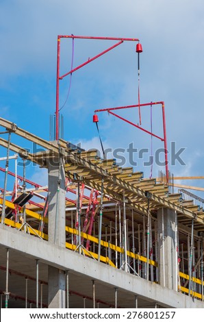 Small cranes and concrete formwork supported by adjustable metal posts on the office building construction site