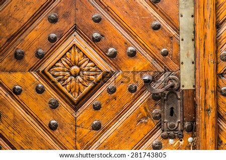 Old wooden door with handle decorated with flower carved in wood