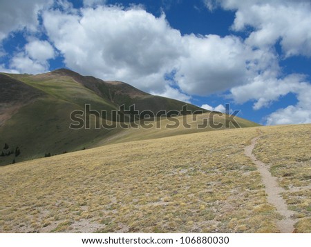 An alpine trail leads to blue skies.