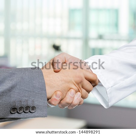 Doctor and businessman shaking hands in office