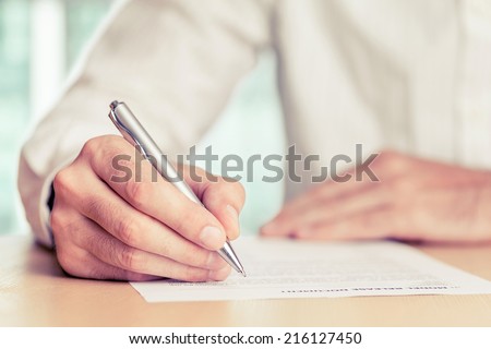 Businessman signing a document. Tinted photo, shallow depth of field.