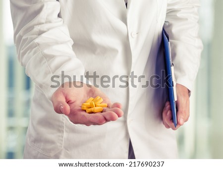 Doctor holding yellow pills in his hand at office. Toned photo