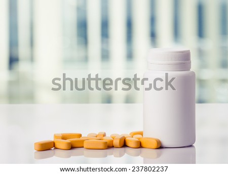 Yellow pills and pills bottle on a white table,toned photo.