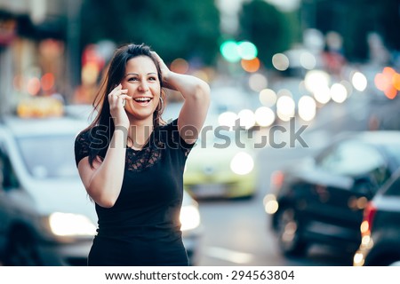 Young beautiful woman talking on her smart phone, traffic jam in background. Toned photo.