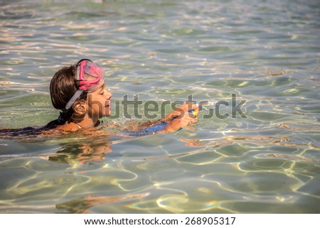 Little girl swimming in diving mask with board for swimming, warm tone