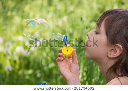 Little girl inflates soap bubbles in the park