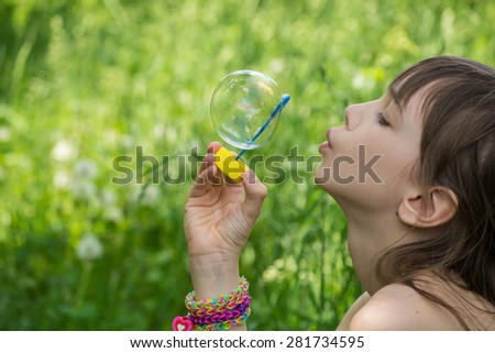 Little girl inflates soap bubbles in the park
