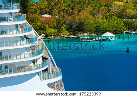 Side of a cruise ship with trees and ocean in background