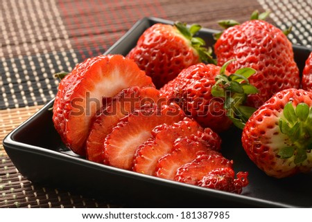 Single well formed strawberry with leaves in group of strawberries.