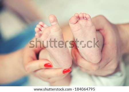 The legs of a new born in the hands of parents