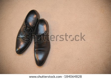 Stylish black shoes lying on a brown rug