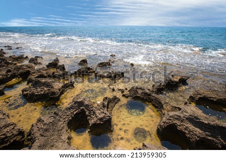 receding sea coastline and stone with water pits