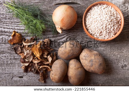 Dried mushrooms, potato, onion, dill and grain in a bowl on a old wooden board