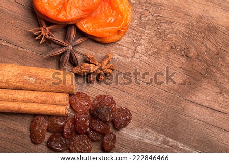 Raisins, cinnamon, anise and dried apricots lying on an old wooden table.