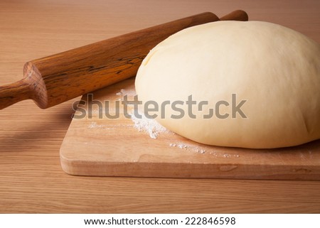 dough on a board and rolling pin with flour for sprinkling