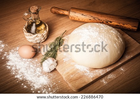 dough on a board with flour. olive oil, eggs, rolling pin, garlic